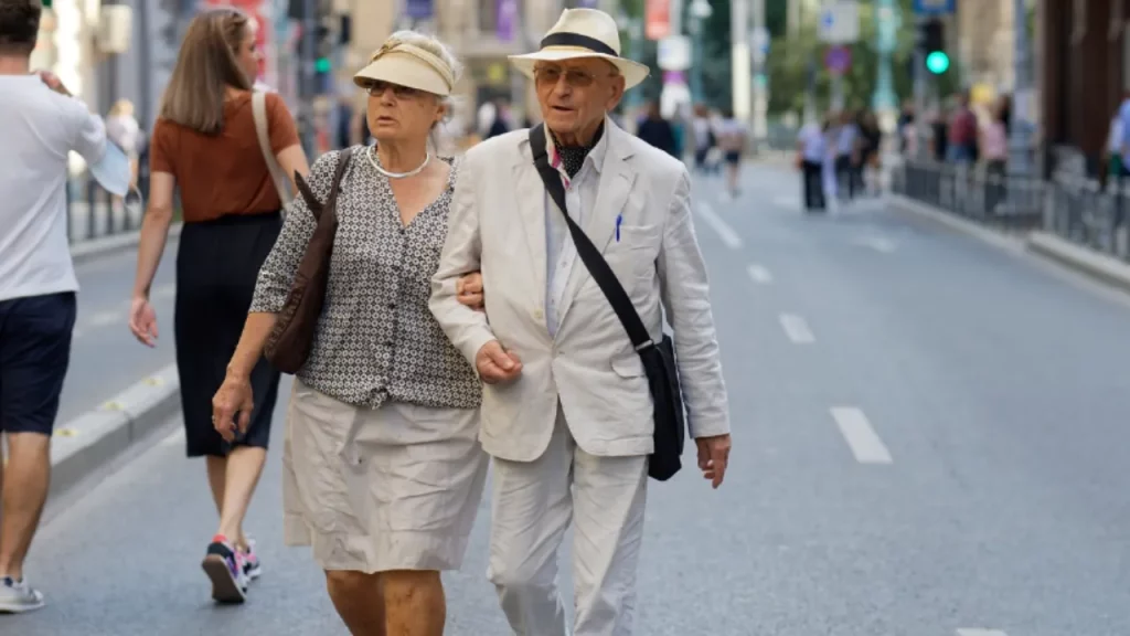 Casal de idosos bem vestidos passeando em via publica.