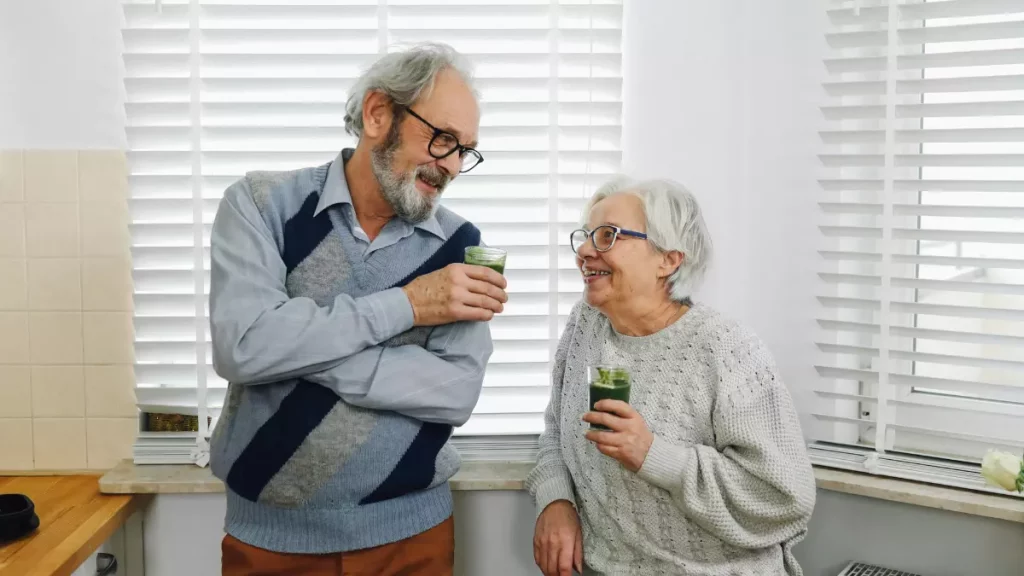 Casal de idosos saudáveis sorrindo enquanto tomam suplemento natural em casa