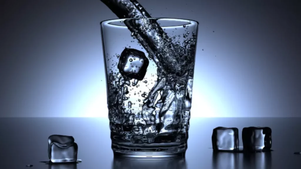 copo sendo adicionado agua com cubos de gelo
